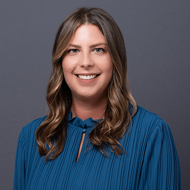 A professional headshot of Kelly with a gray background.