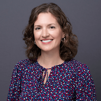 A professional headshot of Becky with a gray background.