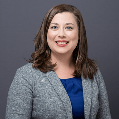 A professional headshot of Carolyn with a gray background.