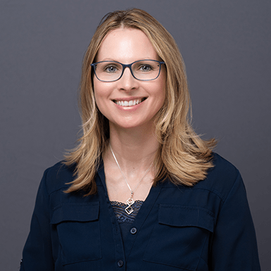 A professional headshot of Janine with a gray background.