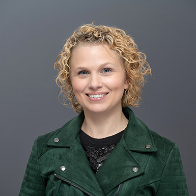 A professional headshot of Joy with a gray background.